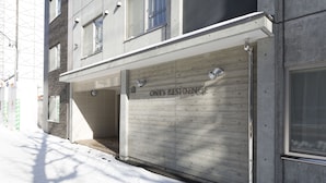 Un edificio con una puerta de garaje con la etiqueta "ONES RESIDENCE" y un acceso cubierto.