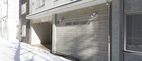 A building with a garage door labeled "ONES RESIDENCE" and a covered entrance.