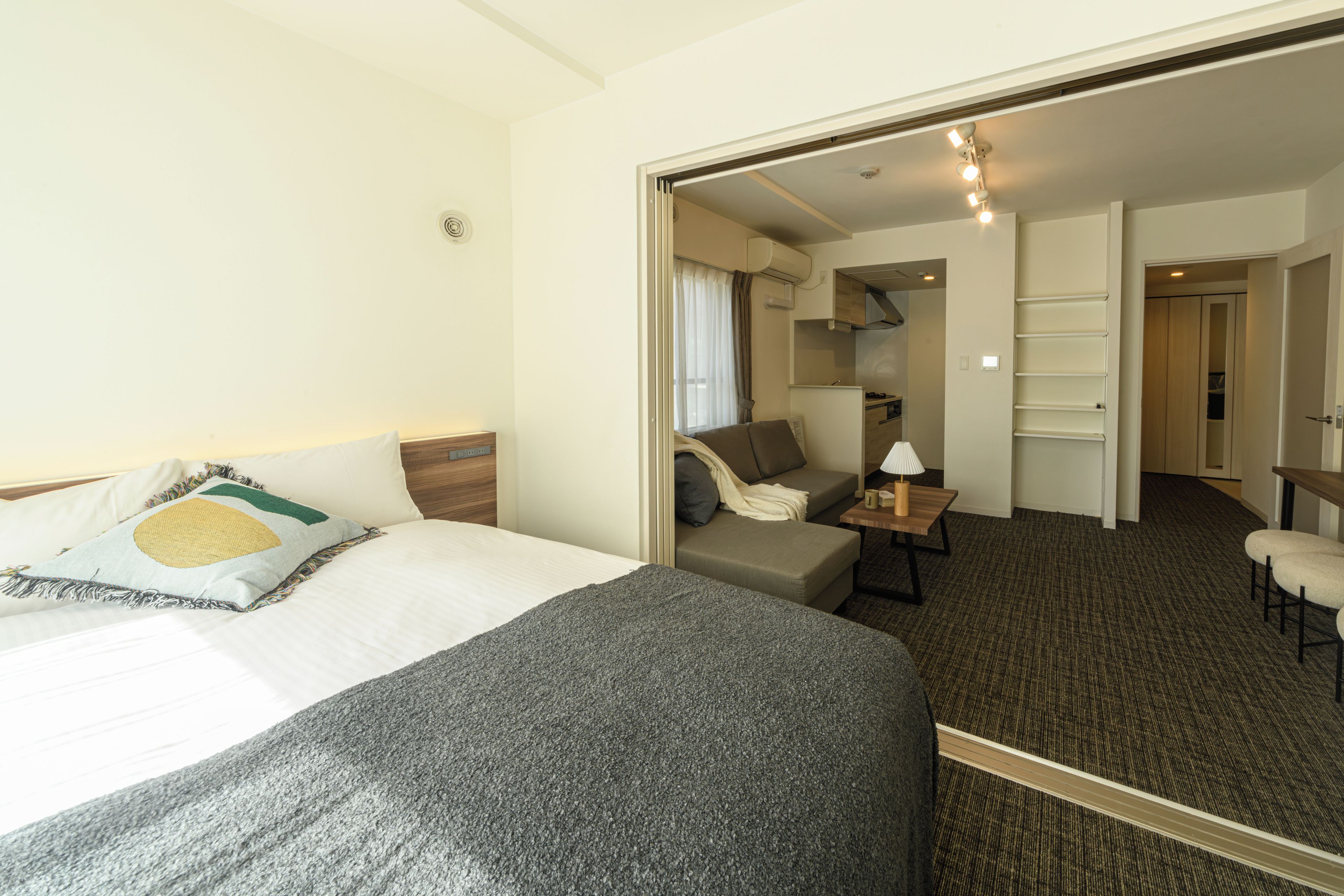 Una habitación de hotel con cama, sofá, una mesita y un espejo.