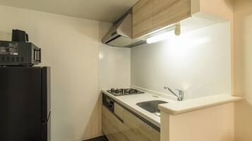 A compact kitchen with a black refrigerator, a stove, and a microwave.