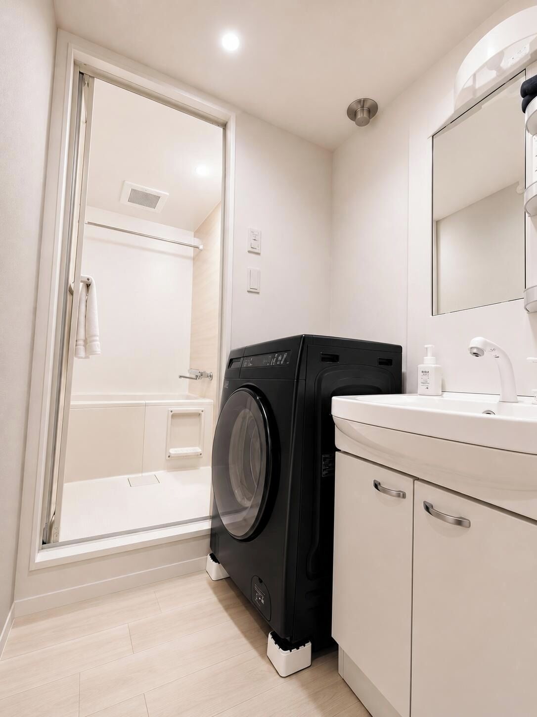 A modern bathroom with a washing machine, a sink, and a mirror.