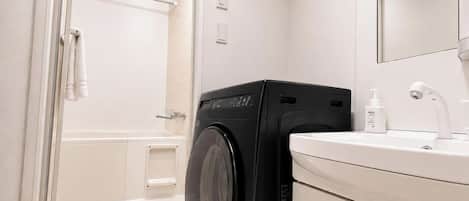 Un baño moderno con lavadora, lavamanos y espejo.