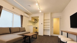 Una sala de estar moderna con un sofá, una mesa de centro, un televisor y una zona de cocina.