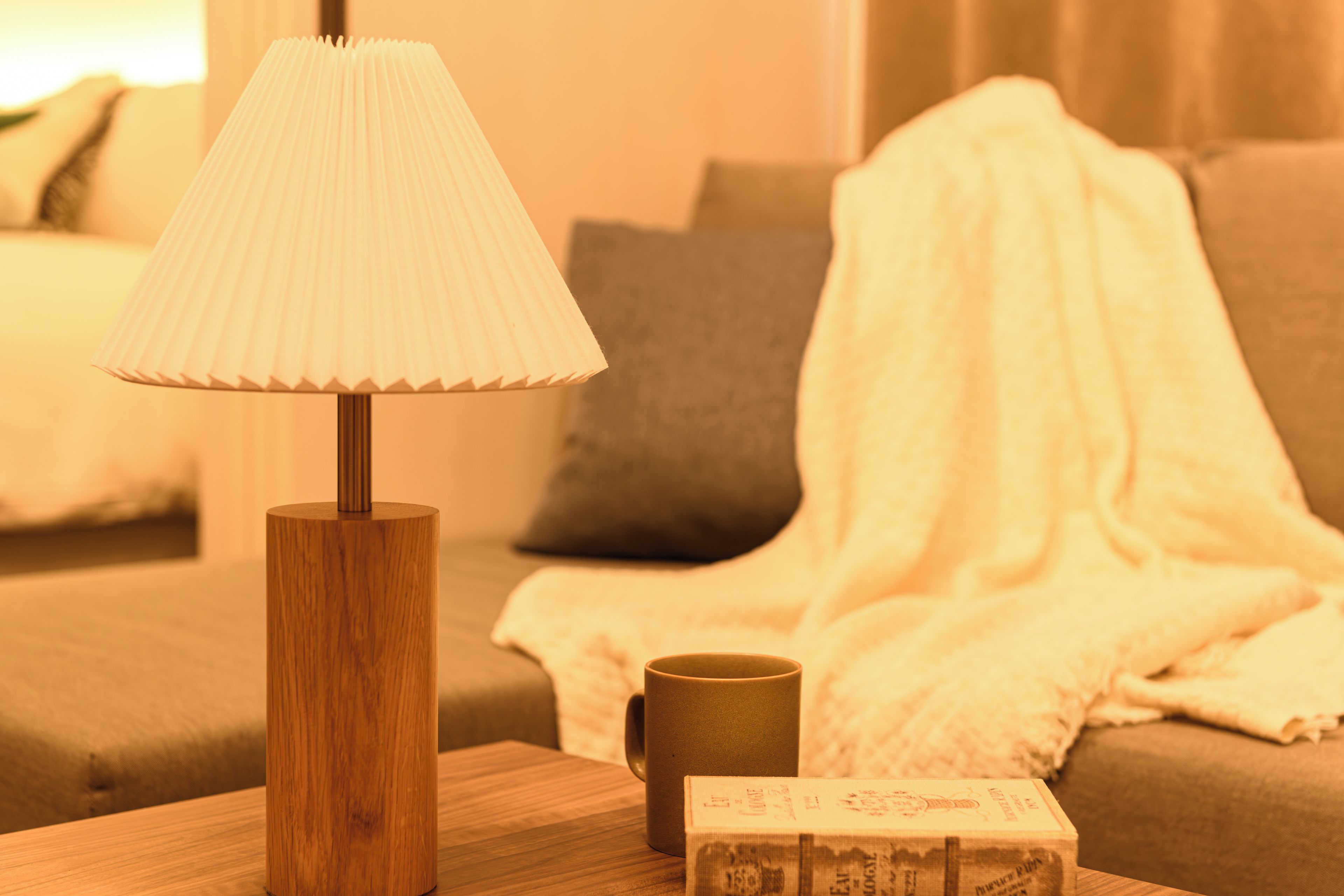 A wooden table with a lamp, a cup, and a box.