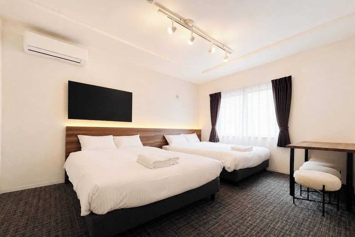 A hotel room with two beds, a flat-screen TV, a desk, and a chair.