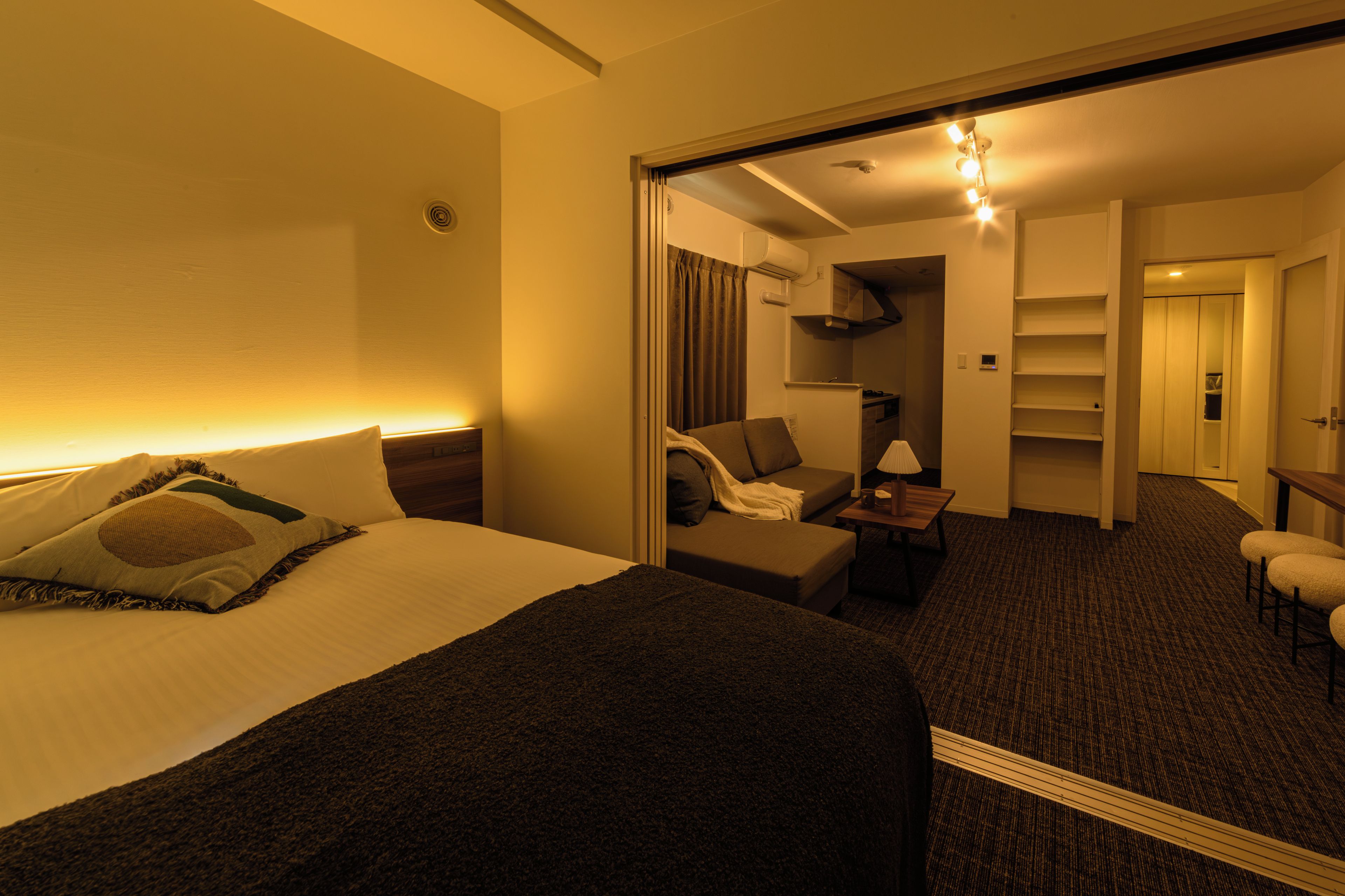 Une chambre d’hôtel avec un lit, un canapé, un bureau et un miroir qui reflète la pièce.