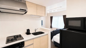 Una kitchenette compacta con estufa, lavamanos y microondas.