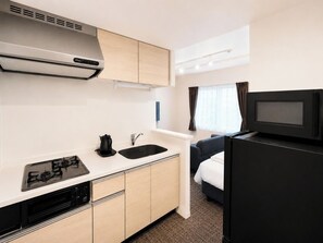 A compact kitchenette with a stove, sink, and microwave. - Hotel ONE'S RESIDENCE (Sapporo)