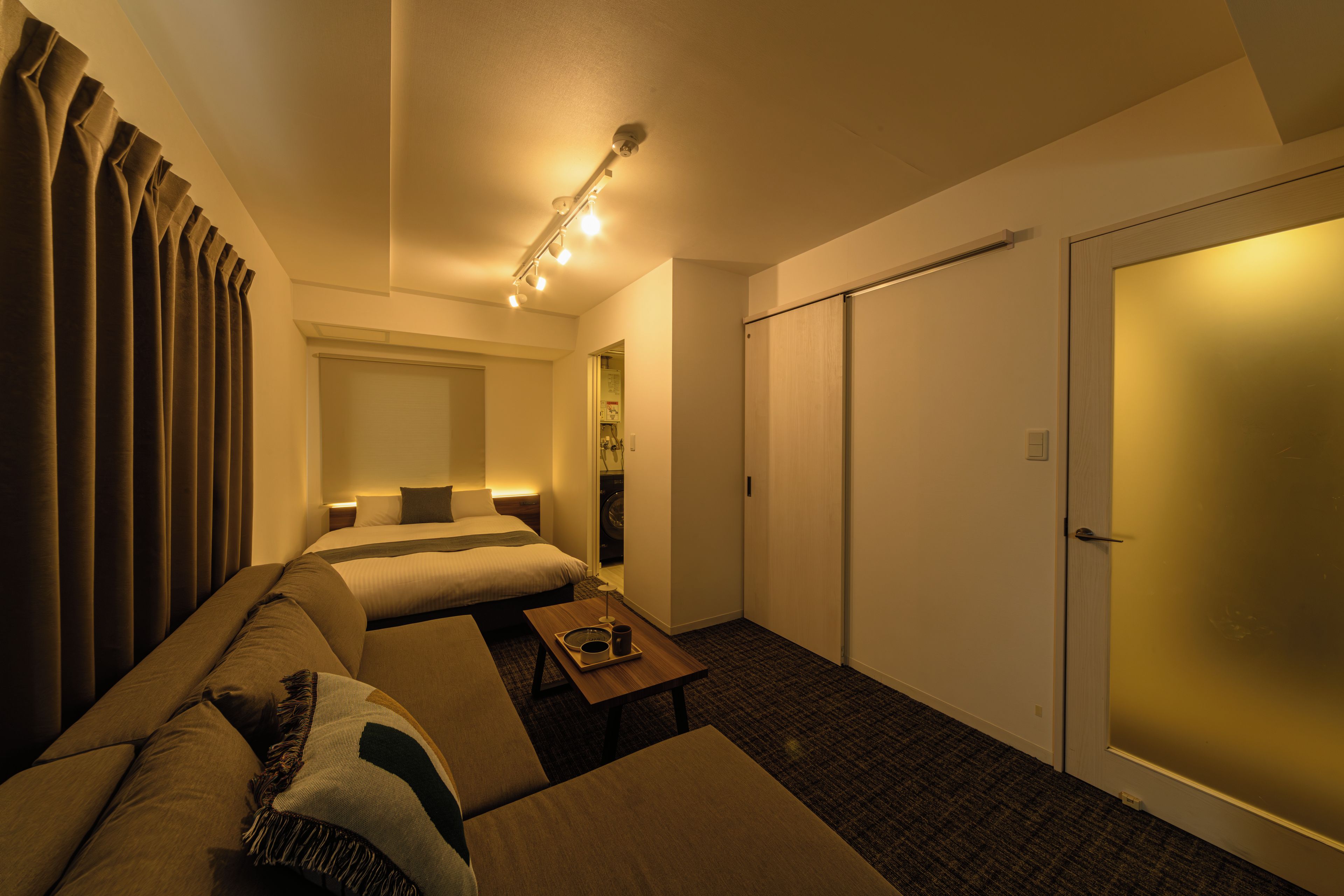 A hotel room with a bed, a sofa, a small table, and a wardrobe.