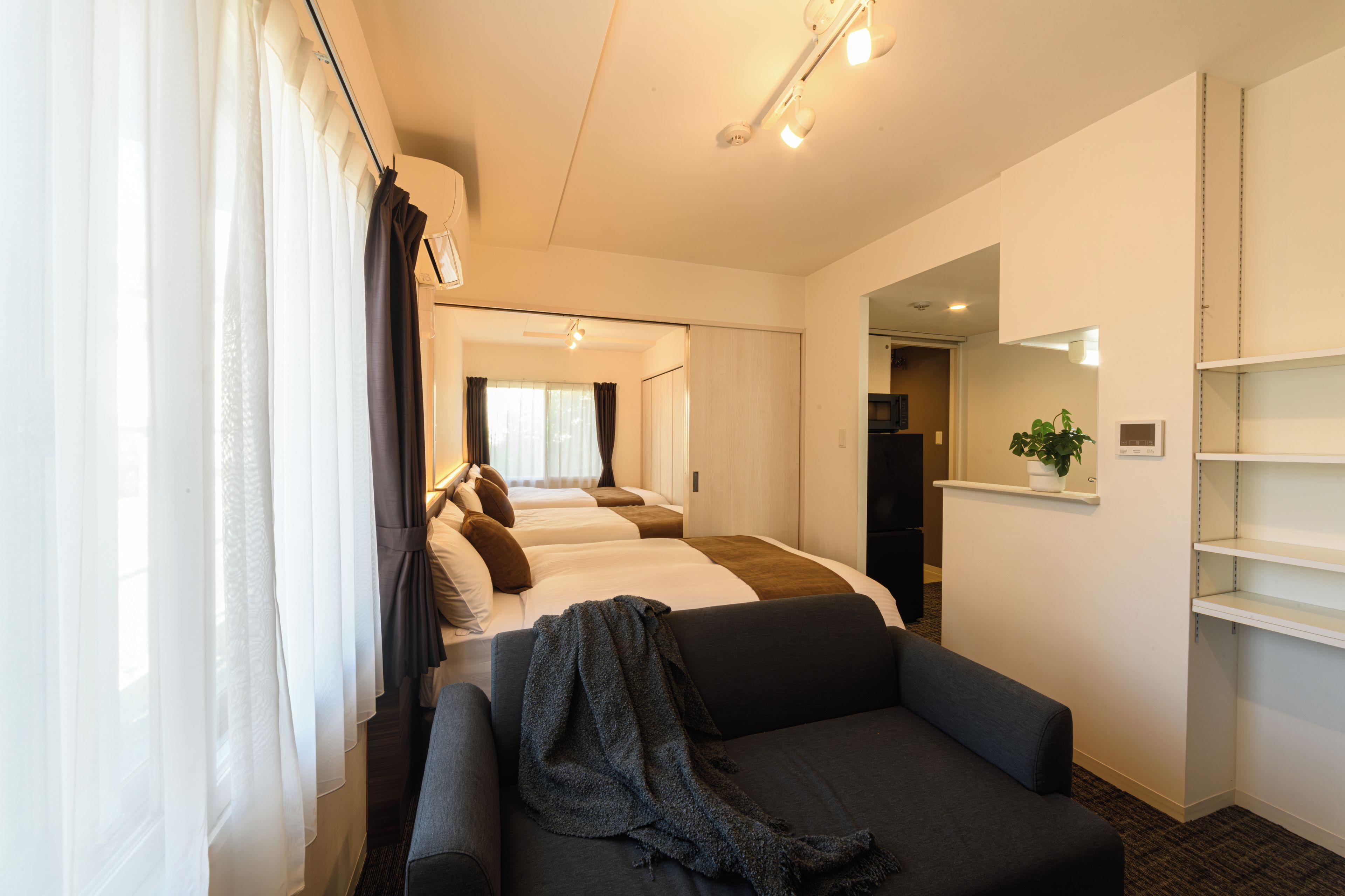 A hotel room with a sofa, a bed with multiple pillows, a small table, and a mirror on the wall.