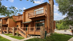 Ein zweistöckiges Gebäude mit Holzfassade, Steinpfeilern und einem Balkon im oberen Geschoss.