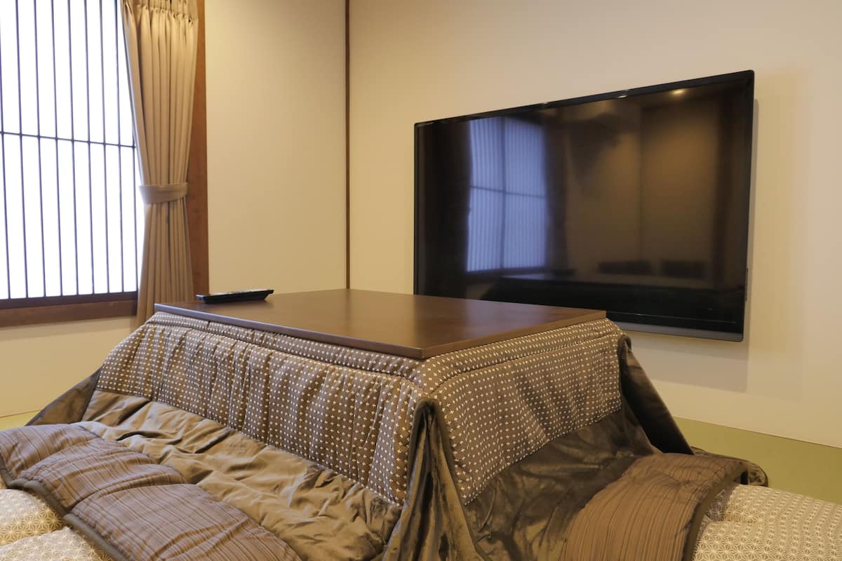 Quarto com uma cama, televisão de tela plana na parede e janela com persianas.