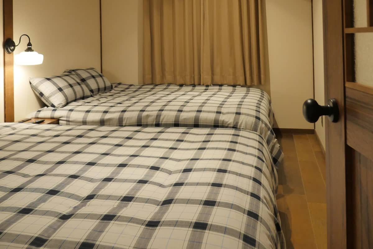 Quarto de hotel com cama de casal, mesa de cabeceira, ar condicionado, televisão fixada na parede e porta com puxador.