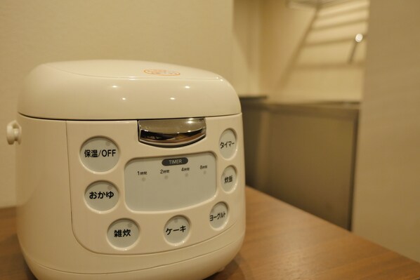 Un electrodoméstico blanco con etiquetas en japonés, que incluye un temporizador y varias configuraciones.