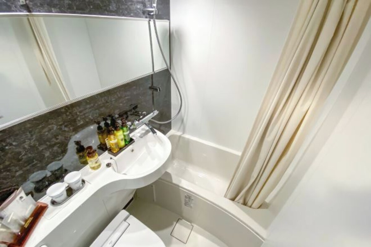Une salle de bain avec un lavabo blanc, un miroir et une douche.
