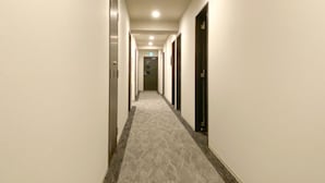 A hotel hallway with carpeted floors, doors on both sides, and a ceiling light. - Hotel Live Max Okayama Kurashiki Station (Kurashiki)