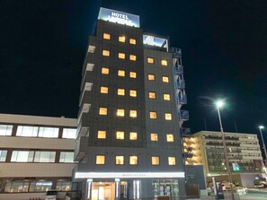 Un hôtel à plusieurs étages, avec des fenêtres illuminées et une enseigne indiquant qu’il s’agit d’un hôtel.