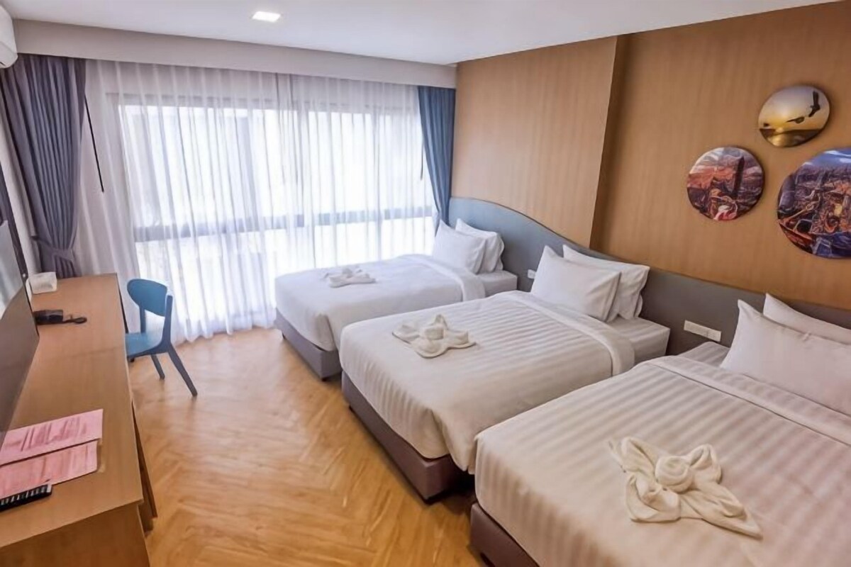 A hotel room with two beds, a desk, and a chair.
