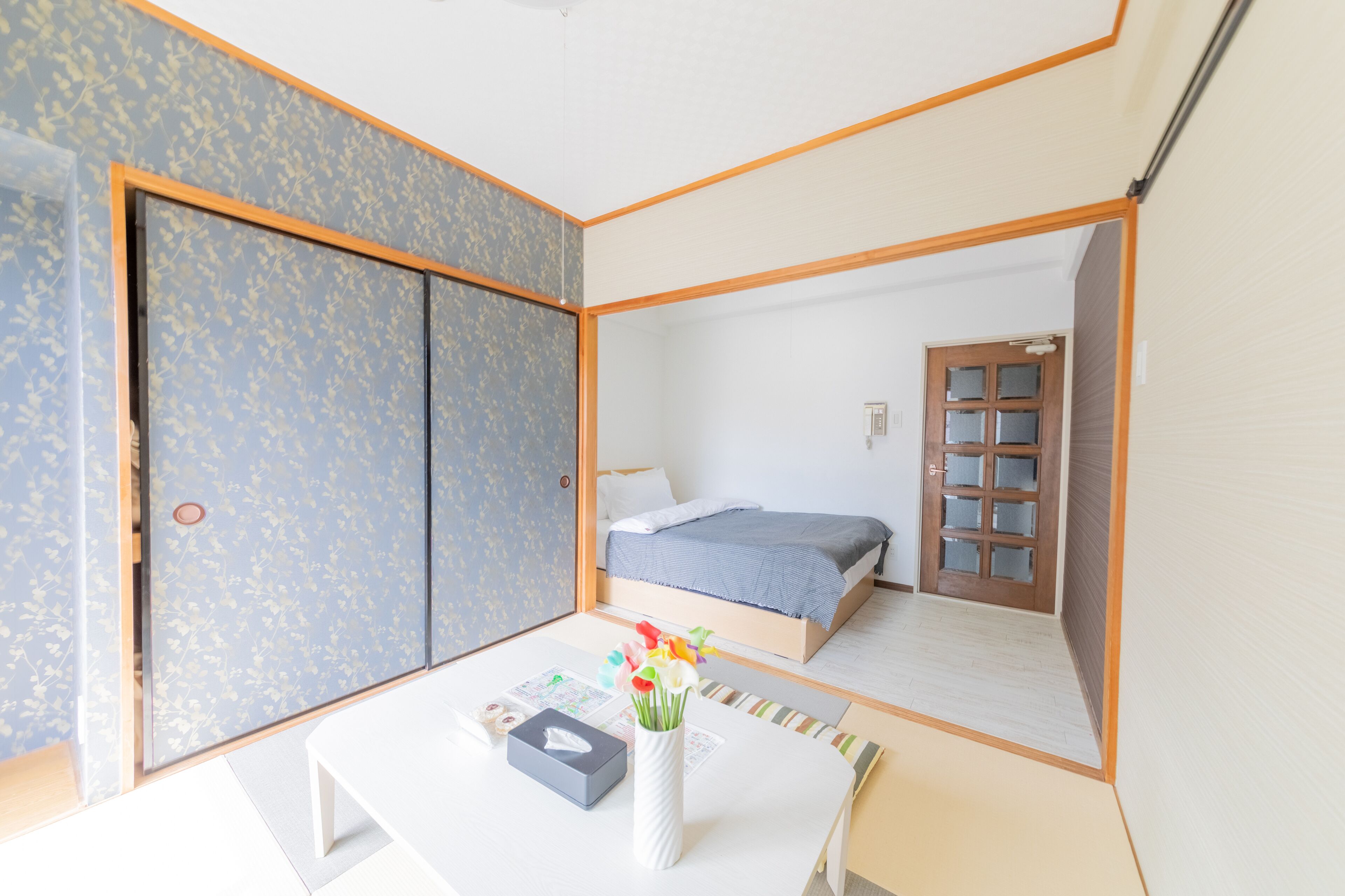 A room with a bed, a table with a vase of flowers, and a wardrobe.