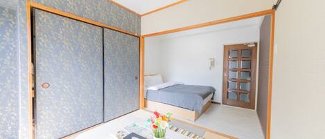 A room with a bed, a table with a vase of flowers, and a wardrobe.