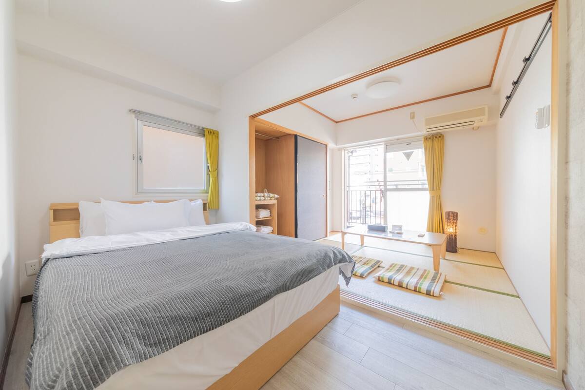 Quarto de hotel moderno com uma cama grande, uma mesinha e vista para a varanda.