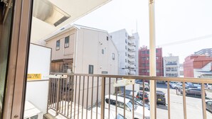 A view from a balcony overlooking a parking lot with several cars and buildings in the background. - SUNDAY peace room Honkawa II (Hiroshima)