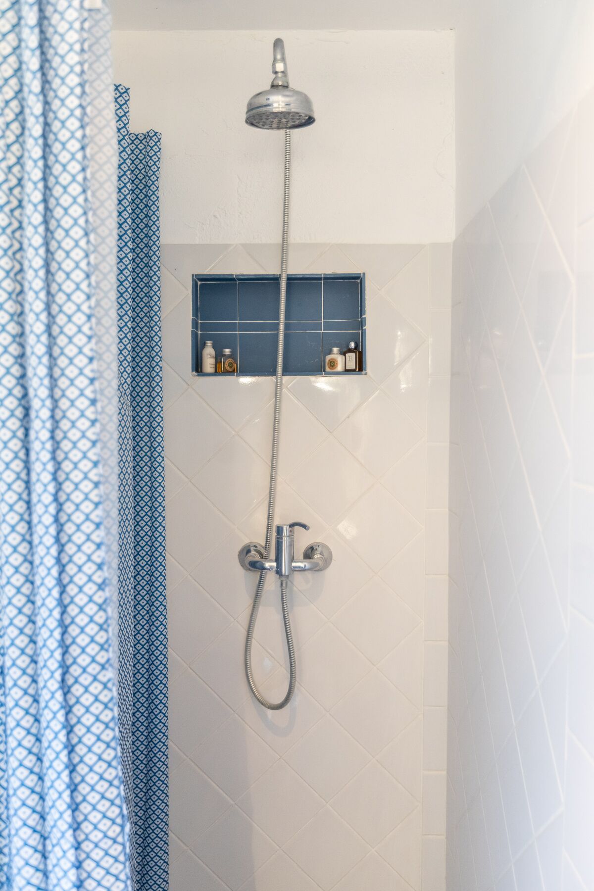 A shower with a handheld showerhead and a wall-mounted control.