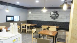 A hotel room with a kitchenette, a seating area with tables and chairs, and a wall-mounted sign reading "HOTEL CHICAGO BOUTIQUE". - Hotel Chicago (Changwon)