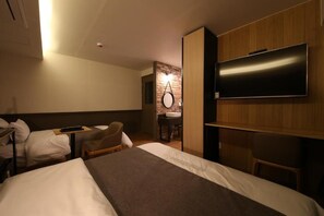 A hotel room with a large bed, a TV mounted on the wall, a desk with a chair, and a small bathroom area with a mirror and sink. - Hotel Chicago (Changwon)