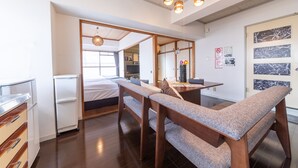 A modern hotel room with a wooden bench, a small table, a refrigerator, and a bed. - SUNDAY peace room Nakashima (Hiroshima)