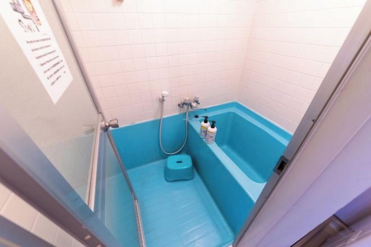 Kylpyhuone, jossa on sininen kylpyamme, suihku ja wc.