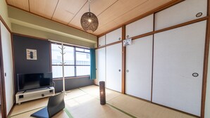 A traditional Japanese room with tatami flooring, a television on a low stand, sliding doors, and a hanging light fixture. - SUNDAY peace room Nakashima (Hiroshima)
