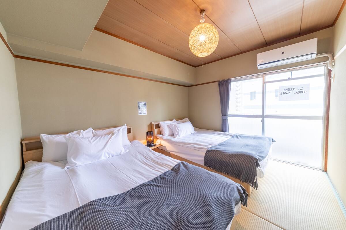Ein Hotelzimmer mit zwei Betten, einer Deckenleuchte, einer Klimaanlage und einem Fenster mit Blick.