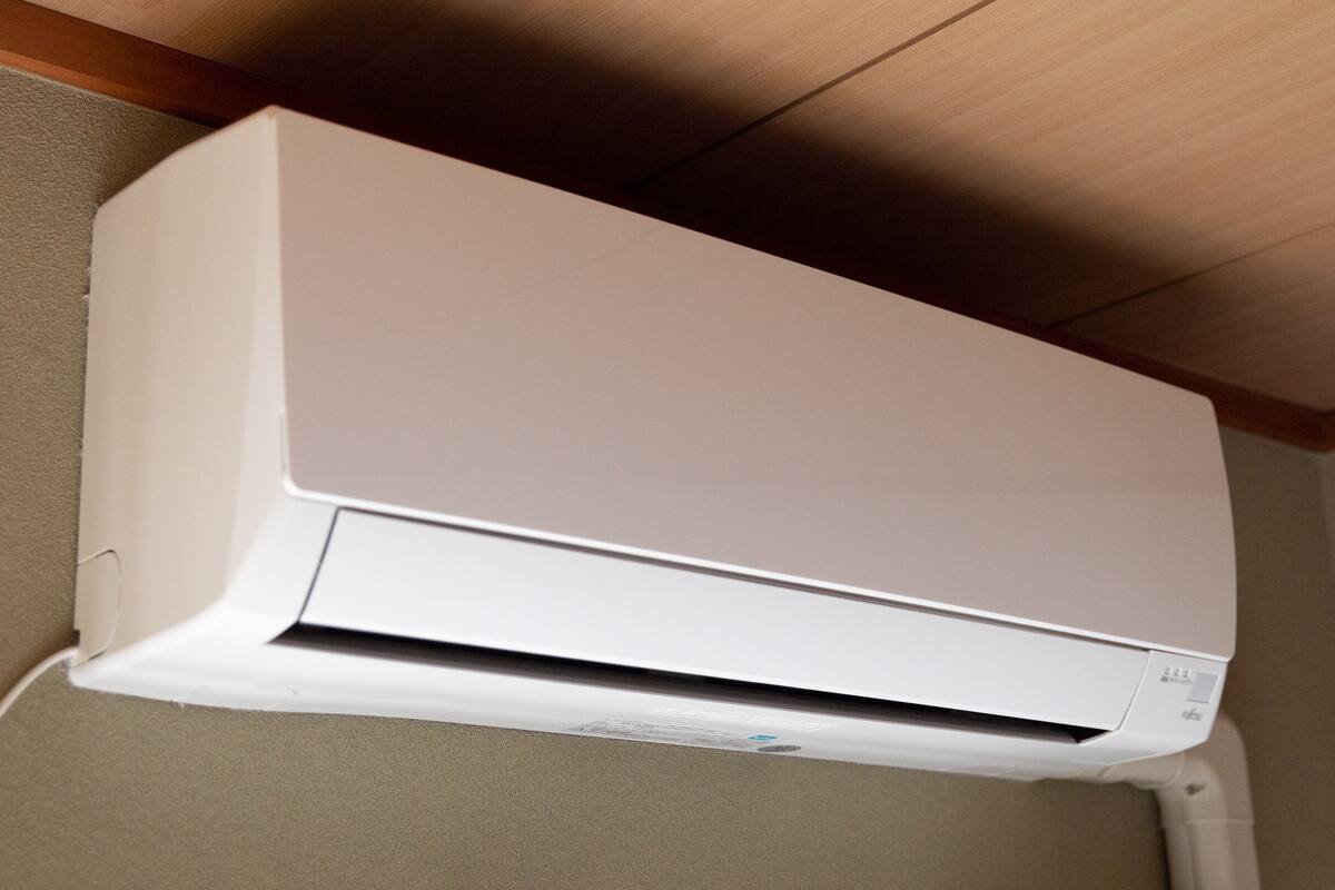 Eine weiße Klimaanlage an einer Wand, darüber ein Holzboden.