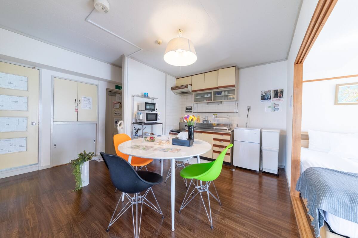 A compact kitchen with a round table, modern chairs, and a microwave.