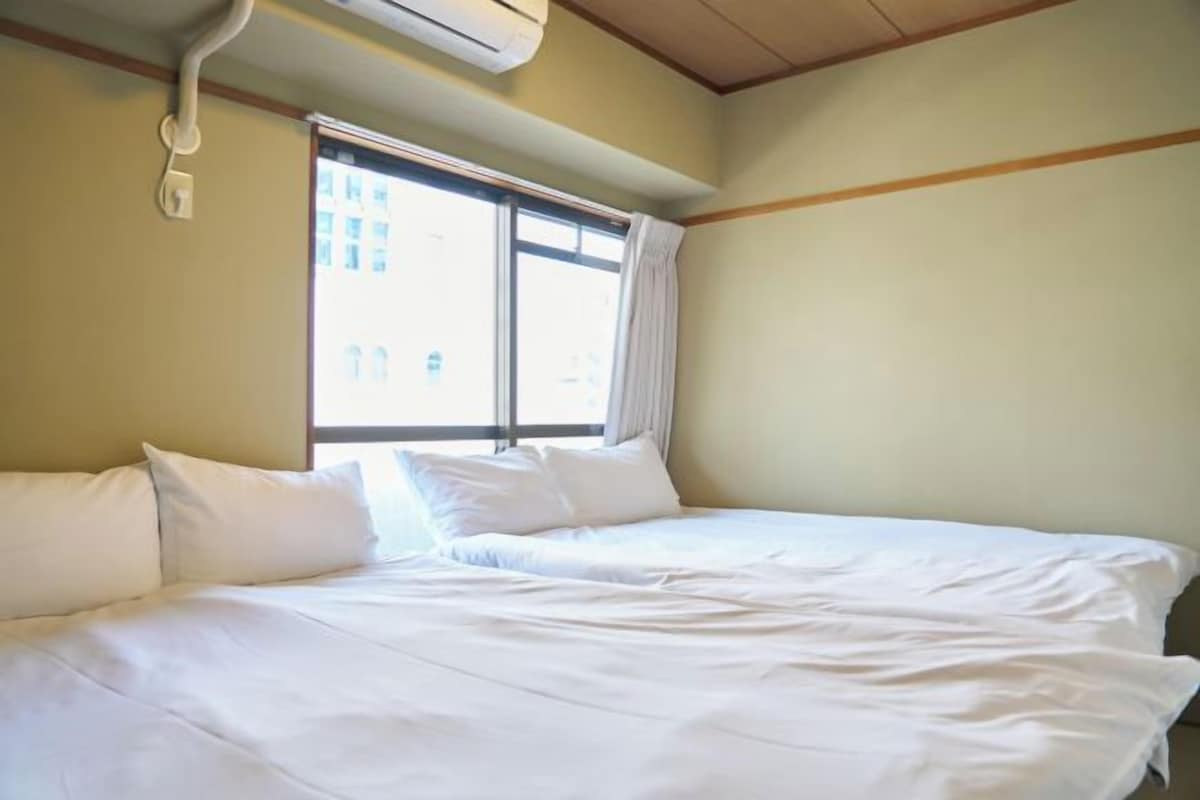 A room with a bed, a window, and an air conditioning unit.