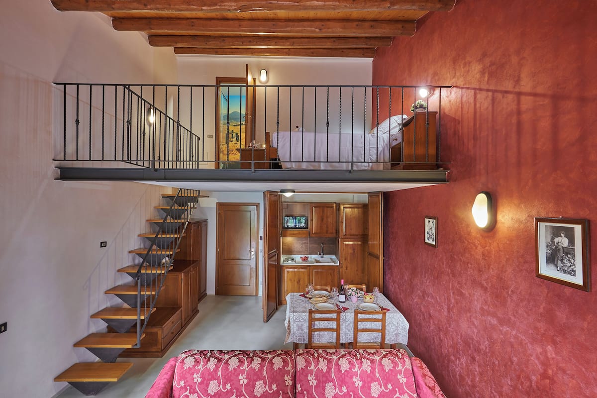 Ein mehrgeschossiges Zimmer mit einer Treppe, einem Essbereich mit Tisch für zwei Personen und einer Küchenzeile.