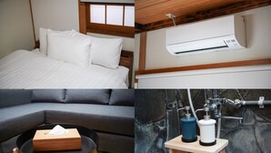 Een bed met witte beddengoed, een grijze bank, een klein rond tafeltje met een doos, en een stenen muur met een waterpartij.