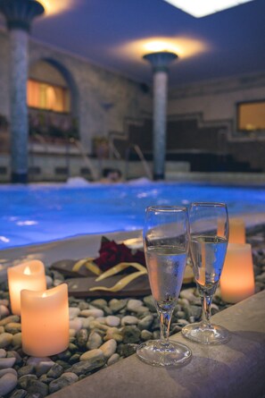 Zona junto a la piscina con dos vasos de agua, velas y un camino de piedra.