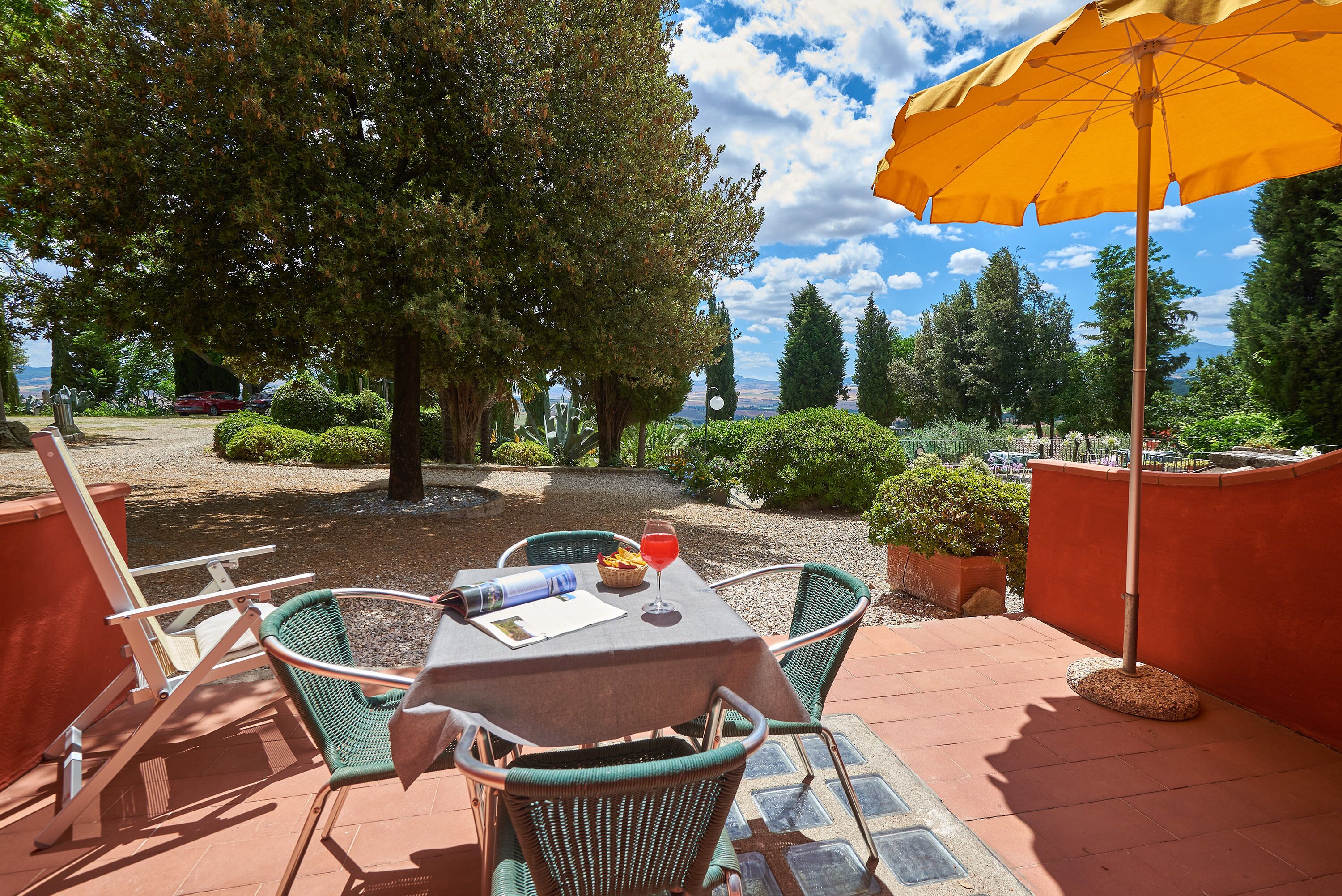 Un patio al aire libre con una mesa, sillas y una sombrilla.