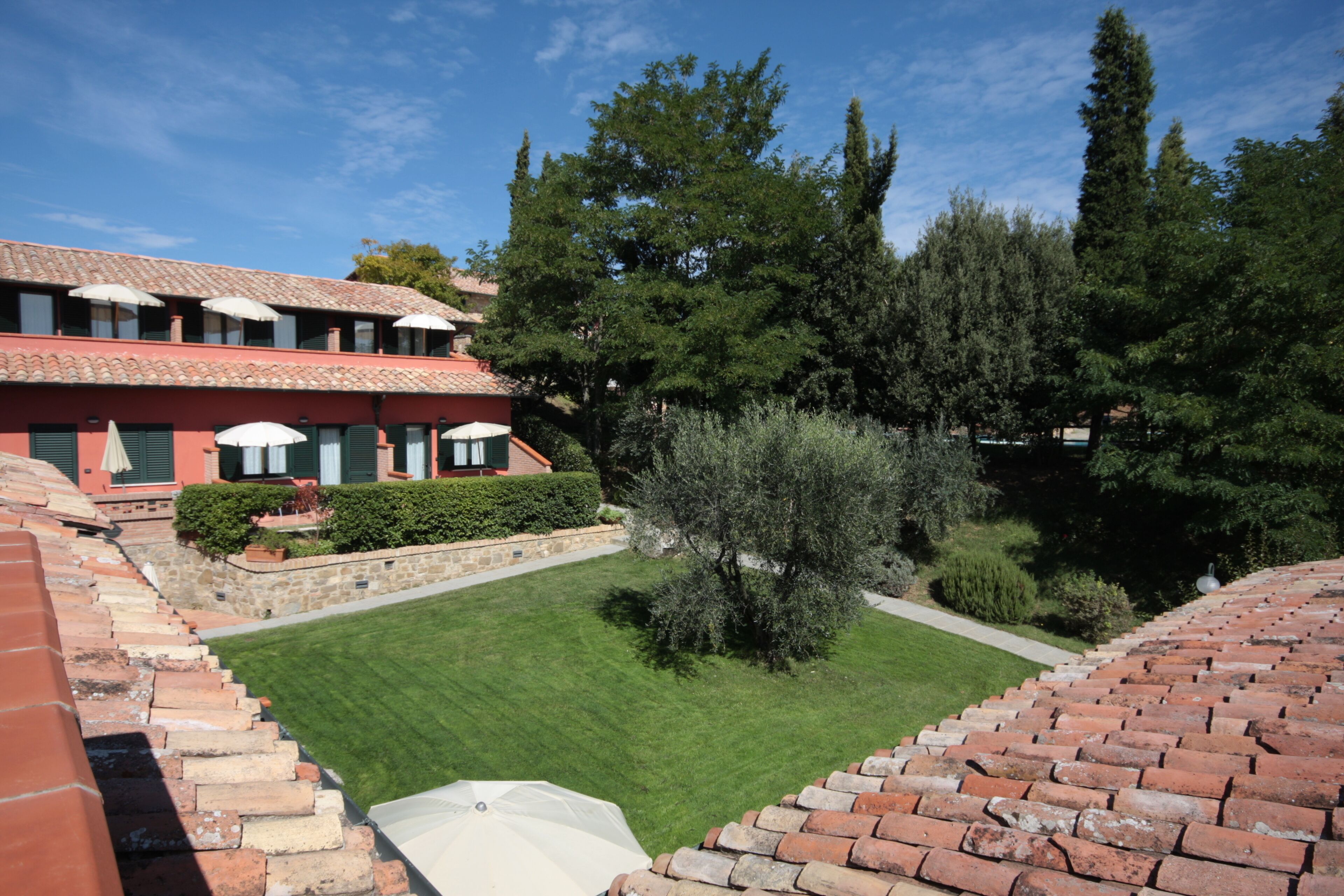 A courtyard with a brick pathway leading to a building with red walls and green shutters.