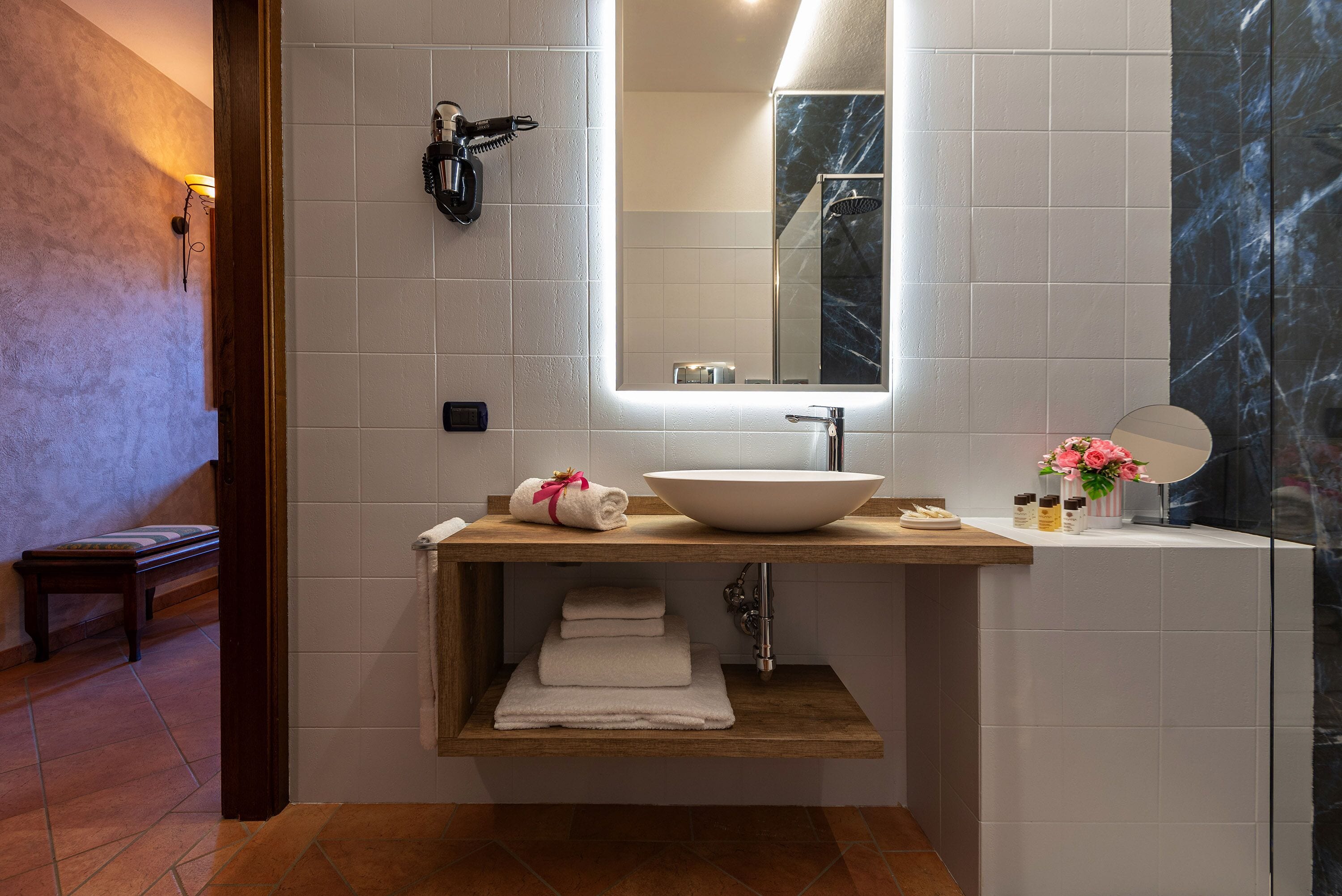 Ein modernes Badezimmer mit einem großen Spiegel, einem Aufsatzwaschbecken und einem Holzregal mit Handtüchern.