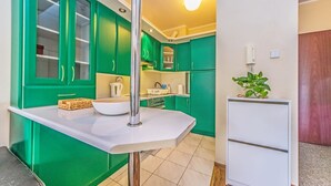 A compact kitchen with green cabinets, a white countertop, and a white refrigerator. - Victus Apartamenty - Poggio (Sopot)