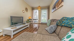 A living room with a TV, sofa, and a dining area with a table and chairs. - Victus Apartamenty - Poggio (Sopot)