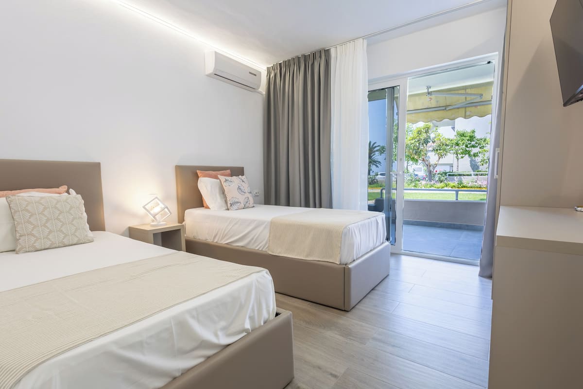 A hotel room with two beds, a large window, and a view of the outdoors.