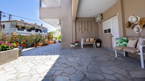 A patio with stone flooring, outdoor seating, potted plants, and a wall with decorative items. - By the Sea (Kassandra)