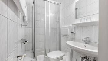 Ein modernes Badezimmer mit Duschkabine aus Glas, einer weißen Toilette und einem Waschbecken mit Spiegel darüber.