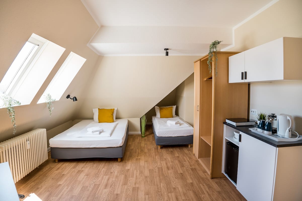 Quarto moderno e compacto com duas camas, uma cozinha compacta e teto inclinado com claraboias.