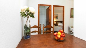 A dining table with a vase of white flowers and a bowl of fruit.
