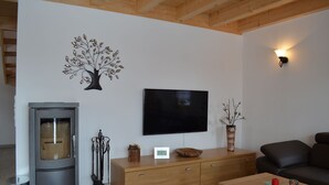 Een moderne woonkamer met een open haard, een flatscreen televisie, een houten kast en een bank.